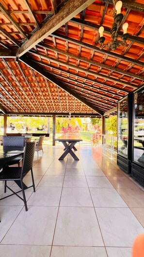 Eine Terrasse im Freien mit Fliesenboden, einem Tisch mit Stühlen und Blick auf einen Garten.