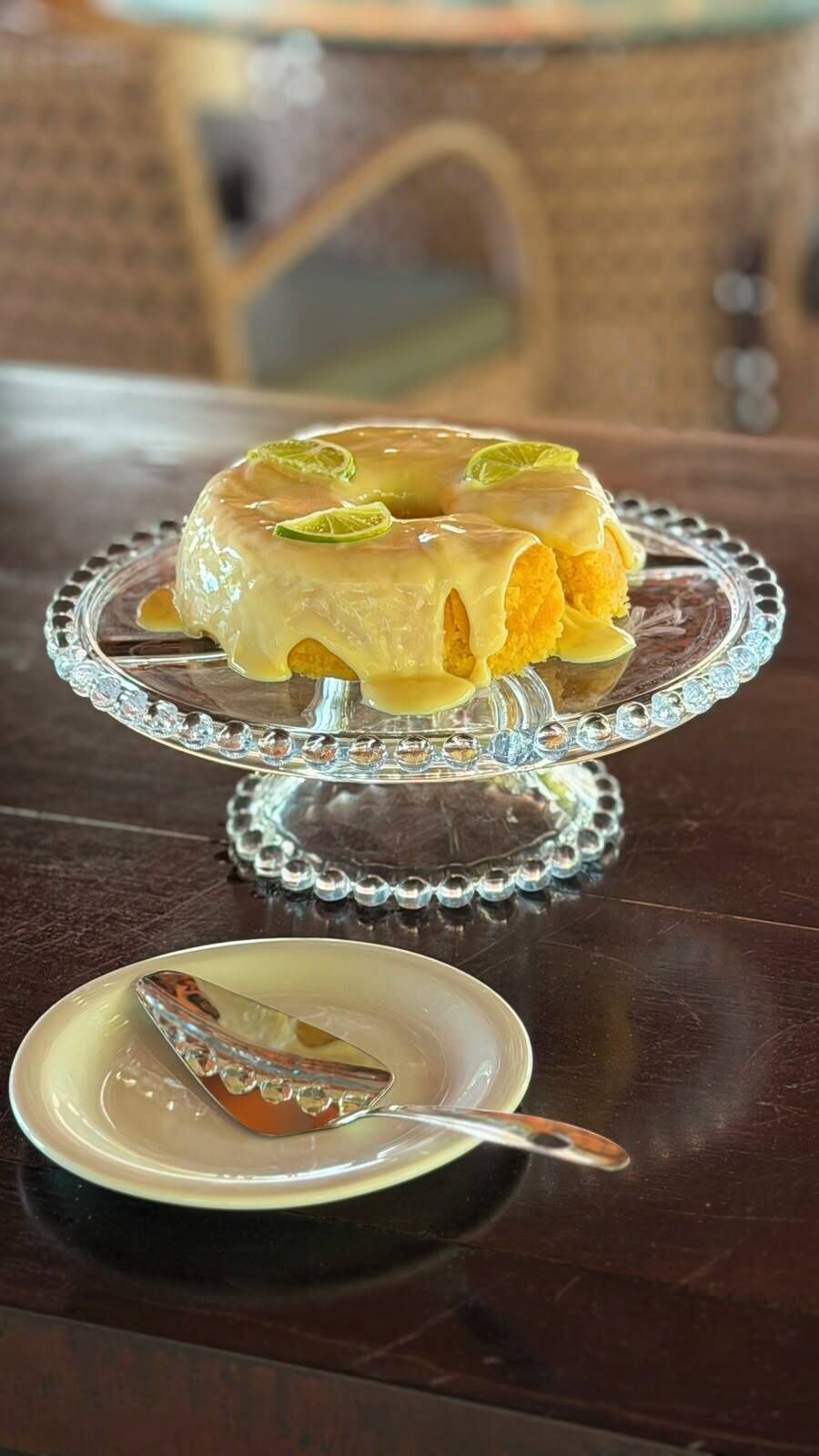 A dessert on a glass cake stand with a spoon on a plate beside it.