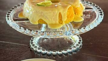 A dessert on a glass cake stand with a spoon on a plate beside it.