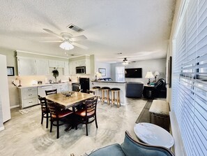 A spacious living area with a dining table, kitchen, and seating area.