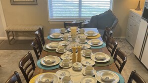 A dining table set for eight with a candle centerpiece, surrounded by chairs. - Hideaway Haven @ Lake Granbury (Granbury)