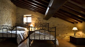 Une pièce rustique avec deux lits en métal, un plafond en bois et des murs en pierre.