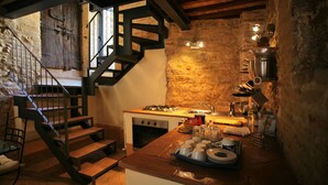 Une cuisine rustique avec un escalier en bois, des murs en pierre et des équipements de base.