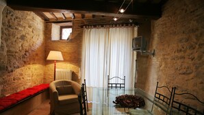 Une pièce rustique avec des murs en pierre, une table en verre, un canapé et une lampe.