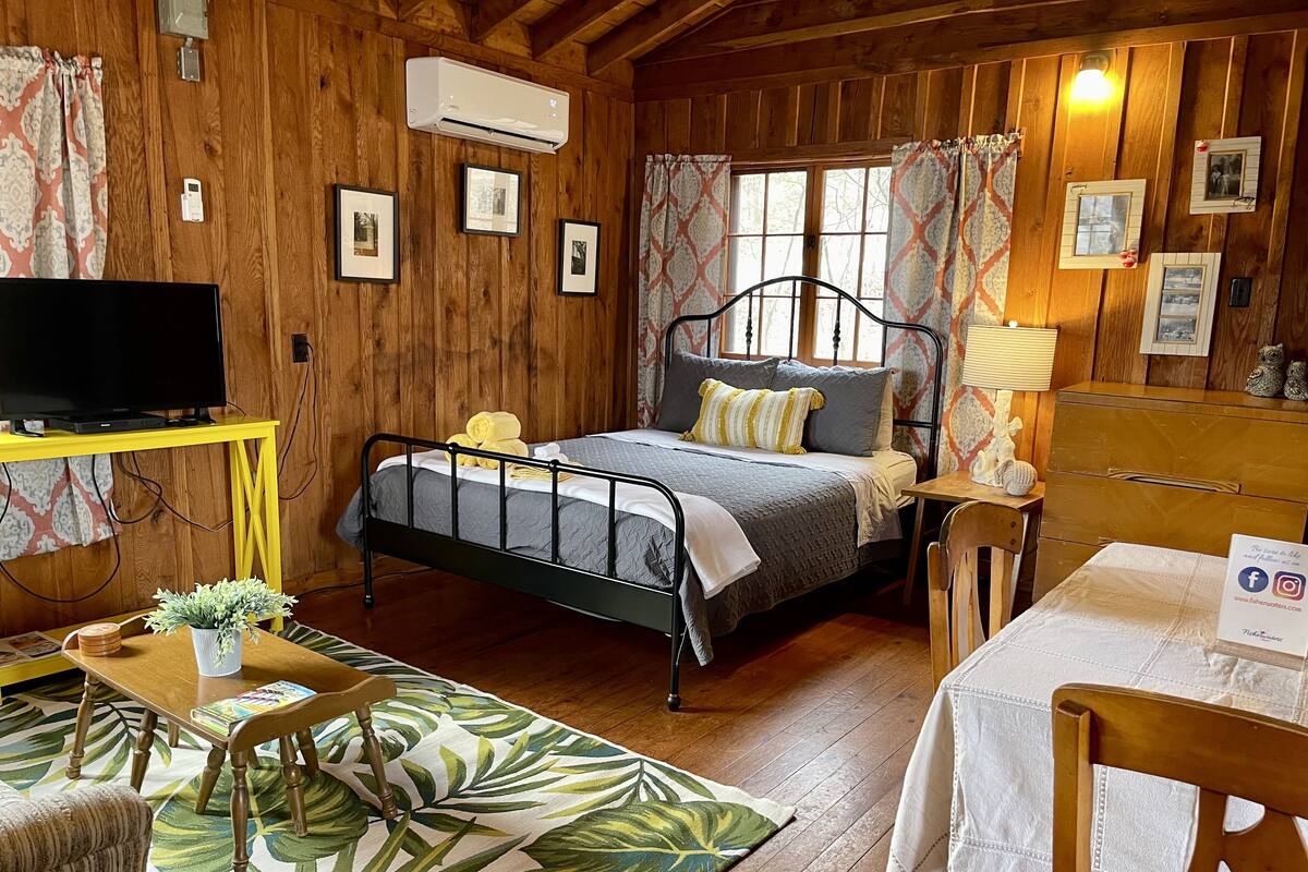 Um quarto acolhedor em estilo cabana, com cama, escrivaninha, televisão e cómoda.