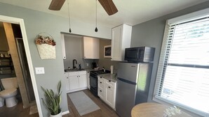 Una cucina moderna con mobili bianchi, elettrodomestici in acciaio inossidabile e un tavolo da pranzo in legno.