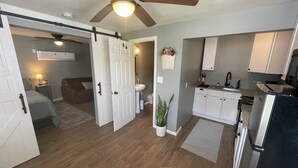 Un'ampia zona living con ventilatore a soffitto, una cucina con mobili bianchi e un'area pranzo con tavolo e sedie.