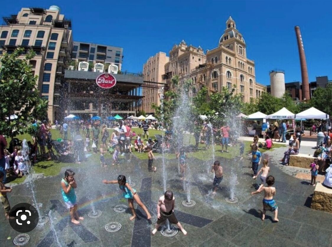 A public square with a water fountain and people around it.