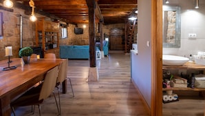 Un interior rústico con una mesa de comedor de madera, sillas, un sofá azul y una chimenea de piedra.