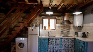 Una cocina rústica con lavadora, refrigerador, fregadero y microondas.