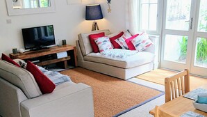 Ein modernes Wohnzimmer mit einer Couch, einem Esstisch und einem Fernseher.