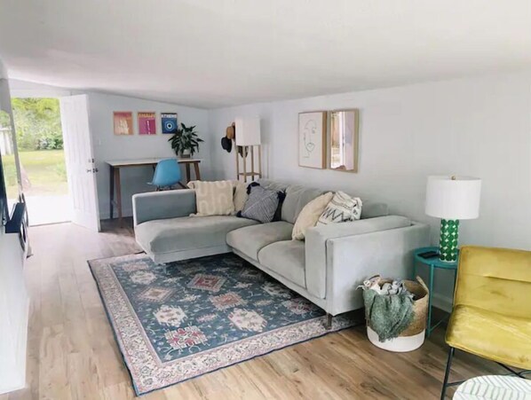 Relax in this inviting living space with a light grey sofa, patterned throw blanket, and comfortable armchairs.