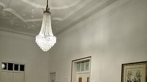 A grand staircase with a white balustrade, a chandelier, and a framed artwork on the wall. - Pias Guesthouse (Serpa)