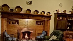 A cozy living room with a brick fireplace, two armchairs, and a leather sofa. - Pias Guesthouse (Serpa)