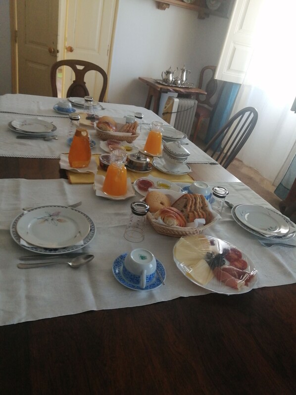 A dining table set with plates, cutlery, and various food items, including bread and fruit. - Pias Guesthouse (Serpa)