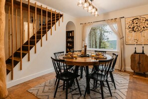 A dining area with a wooden staircase, a round table with chairs, and a view through a window. - Rivers Ledge Cabin with Sauna and Hot Tub (Barrville)