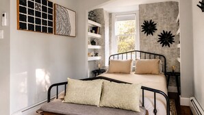 Ein Schlafzimmer mit einem Bett, Nachttischen, einer Bank und Kunstwerken an den Wänden.