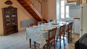 A dining area with a wooden staircase, a wine cabinet, and a kitchen with appliances.