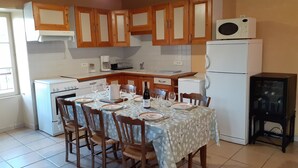 A kitchen with wooden cabinets, a white stove, a refrigerator, and a dining table set for four.