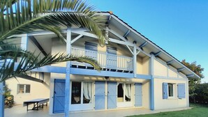 Een twee verdiepingen tellend huis met een balkon, een overdekte patio en een verzorgd gazon.