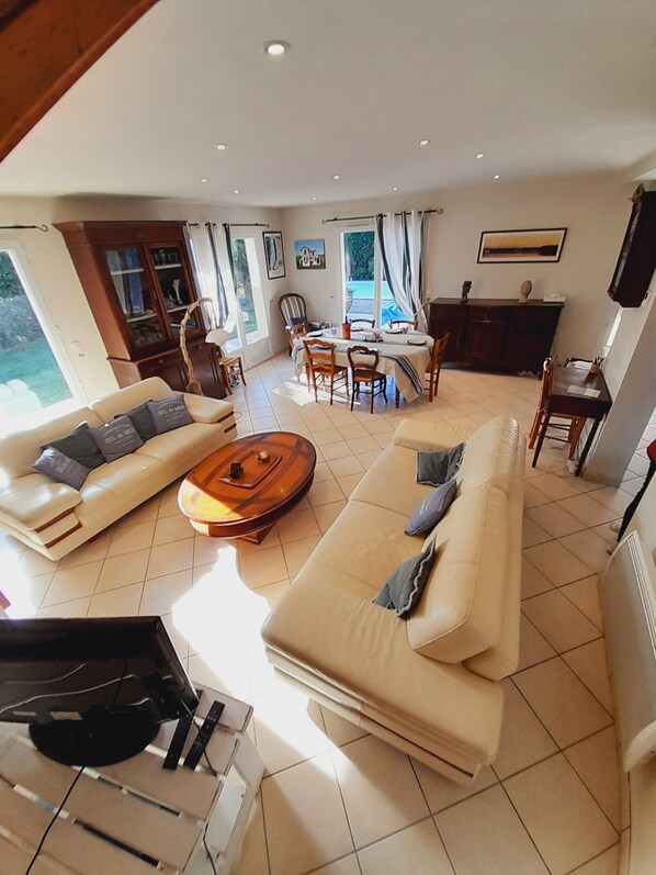 A spacious living room with a sofa set, a coffee table, and a dining area with chairs and a table.