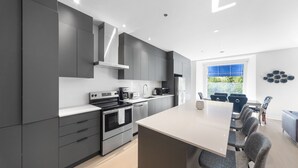 A modern kitchen with grey cabinets, stainless steel appliances, and a central island with seating. - Elegant Suites De La Montagne- Dtwn Mtl (Montreal)