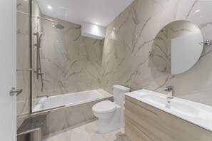 A modern bathroom with a glass-enclosed shower, a white toilet, and a wooden vanity with a sink. - Elegant Suites De La Montagne- Dtwn Mtl (Montreal)