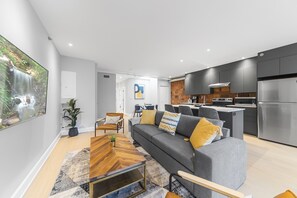 A modern apartment with a living room, dining area, kitchen, and a large window with a waterfall view. - Elegant Suites De La Montagne- Dtwn Mtl (Montreal)
