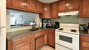 A kitchen with wooden cabinets, a white stove, a microwave, and a granite countertop. - ✨One Bedroom Stunning River Views at Fort Lauderdale (Fort Lauderdale)
