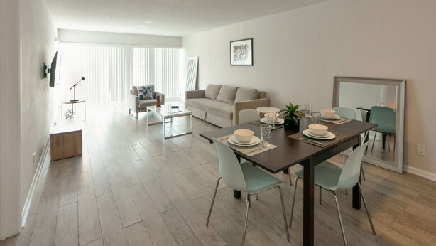 A modern living room with a dining area, a sofa, a coffee table, and a dining table set for four. - ✨One Bedroom Stunning River Views at Fort Lauderdale (Fort Lauderdale)