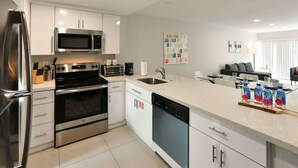 Una cucina moderna con elettrodomestici in acciaio inossidabile, lavastoviglie e zona pranzo con divano e tavolo.