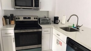 A kitchen with a microwave, toaster, coffee maker, sink, dishwasher, and a stove. - ✨Deluxe Designer Two Bedroom at Fort Lauderdale (Fort Lauderdale)