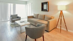 A modern living room with a sofa, armchair, coffee table, and floor lamp. - ✨Deluxe Designer Two Bedroom at Fort Lauderdale (Fort Lauderdale)