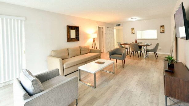 Un salon moderne comprenant un canapé, un fauteuil, une table basse, une table à manger et des chaises.