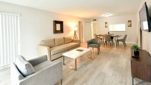 Un salon moderne comprenant un canapé, un fauteuil, une table basse, une table à manger et des chaises.