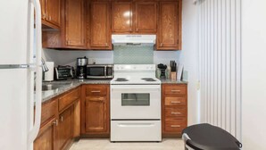 A compact kitchen with wooden cabinets, a white stove, a microwave, and a coffee maker. - ✨One Bedroom Stunning River Views at Fort Lauderdale (Fort Lauderdale)