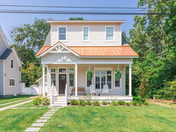 A two-story house with a front porch, a covered entryway, and a small garden area.