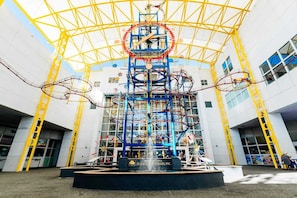 Une grande attraction d’intérieur, avec une structure circulaire centrale entourée d’échafaudages jaunes.