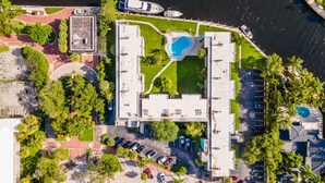 Eine Luftaufnahme eines Hotels mit Pool, Parkplatz und Lage am Wasser.