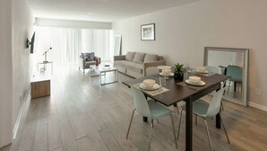 A modern living room with a dining area, a sofa, a coffee table, and a dining table set for four. - ✨Brand New Designer Two Bedroom Apartment at Fort Lauderdale (Fort Lauderdale)