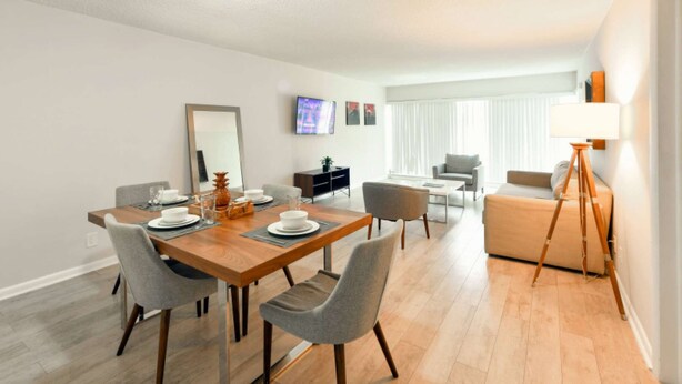 A modern living room with a dining area, a sofa, a lamp, and a TV. - ✨Brand New Designer Two Bedroom Apartment at Fort Lauderdale (Fort Lauderdale)