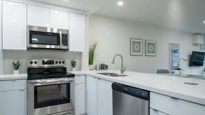 A modern kitchen with stainless steel appliances, white cabinetry, a dishwasher, and a sink. - ✨ New Designer One Bedroom Apartment at Fort Lauderdale (Fort Lauderdale)