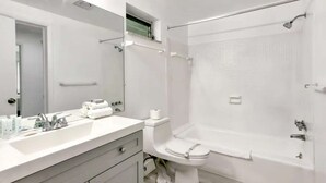 A modern bathroom with a large mirror, a sink with toiletries, a toilet, and a walk-in shower. - ✨ New Designer One Bedroom Apartment at Fort Lauderdale (Fort Lauderdale)