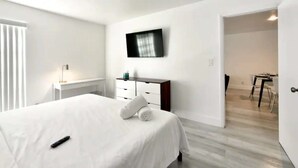 A hotel room with a bed, a desk, a television, and a dining area. - ✨ New Designer One Bedroom Apartment at Fort Lauderdale (Fort Lauderdale)