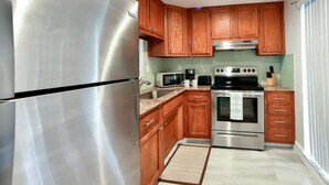 A kitchen with wooden cabinets, stainless steel appliances, a microwave, a coffee maker, and a stove. - ✨ New Designer One Bedroom Apartment at Fort Lauderdale (Fort Lauderdale)