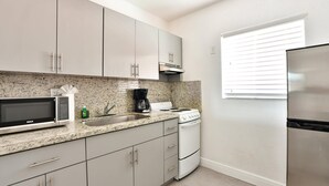 A modern kitchen with granite countertops, stainless steel appliances, and light-colored cabinetry. - ✨Stunning Wynwood Modern Flat - Full Kitchen (Miami)
