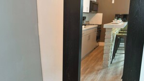 A room with a large mirror reflecting a kitchen area, a wooden floor, and a partial view of a staircase. - ✨ One Bedroom Chic and Cool - Large (Full Kitchen) (Miami)
