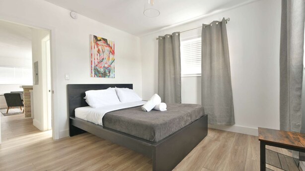 Une chambre moderne avec un grand lit, un plancher en bois et un tableau accroché au mur.