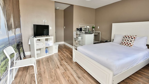 Une chambre d’hôtel équipée d’un lit, d’une télévision, d’un bureau avec un ordinateur, d’une chaise et offrant une vue sur l’extérieur.