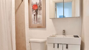 Une salle de bain avec des toilettes, un lavabo et un tableau encadré au-dessus du lavabo.